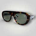 Óculos de sol W One modelo aviador em acetato camuflado marrom com lentes verdes, um design marcante que combina personalidade e sofisticação. O contraste entre a estrutura camuflada e as lentes traz autenticidade ao visual, valorizando o olhar com estilo contemporâneo. No uso diário, a proteção UV400 garante conforto e segurança visual, unindo estética diferenciada e funcionalidade.