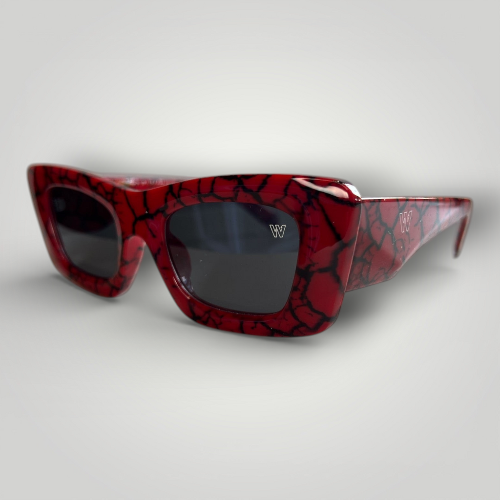 Óculos de sol W One em acetato vermelho marmorizado em preto, um modelo de tirar o fôlego, ousado e cheio de personalidade. O design gatinho traduz luxo e atitude para quem tem estilo e gosta de se destacar. No uso diário, a proteção UV400 garante conforto e segurança visual, unindo impacto estético e funcionalidade em uma peça marcante.