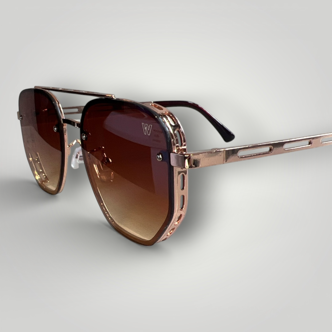 Óculos de sol W One com lentes em degradê marrom e hastes em metal rosé, uma combinação que traduz elegância em cada detalhe. O design contemporâneo e diferenciado transforma a peça em um acessório refinado, ideal para quem valoriza estilo, leveza e autenticidade em um único item.

No uso diário, a proteção UV400 garante conforto e segurança visual, unindo estética sofisticada e funcionalidade.