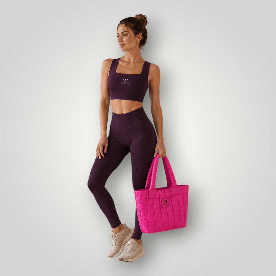 Modelo vestindo conjunto fitness roxo segurando bolsa W One Brand Store Move Puffer rosa estilo acolchoado