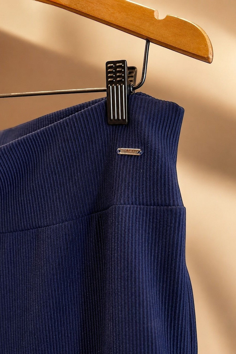 Detalhe da cintura da calça pantalona W One Brand Store azul marinho em tecido canelado com placa metálica da marca