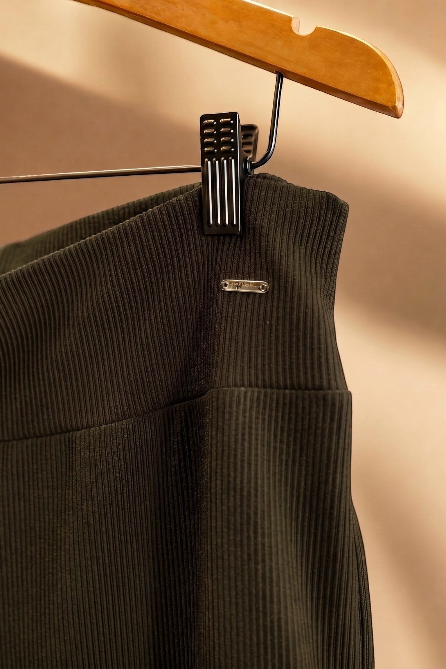 Detalhe do cós da calça pantalona W One Brand Store verde militar em tecido canelado com placa metálica da marca