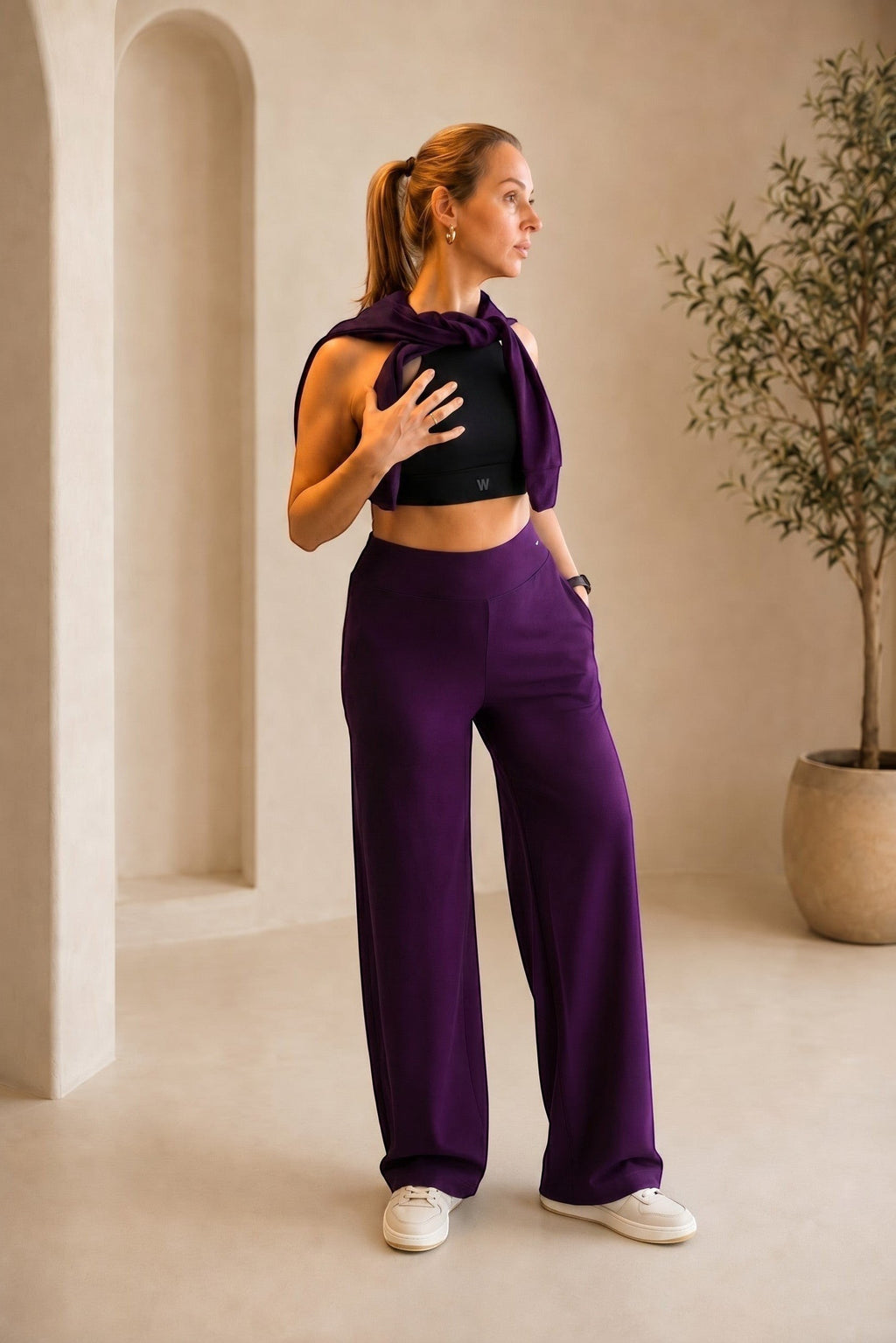 Modelo veste calça pantalona canelada W One Brand Store na cor vinho com blusa preta em ambiente minimalista