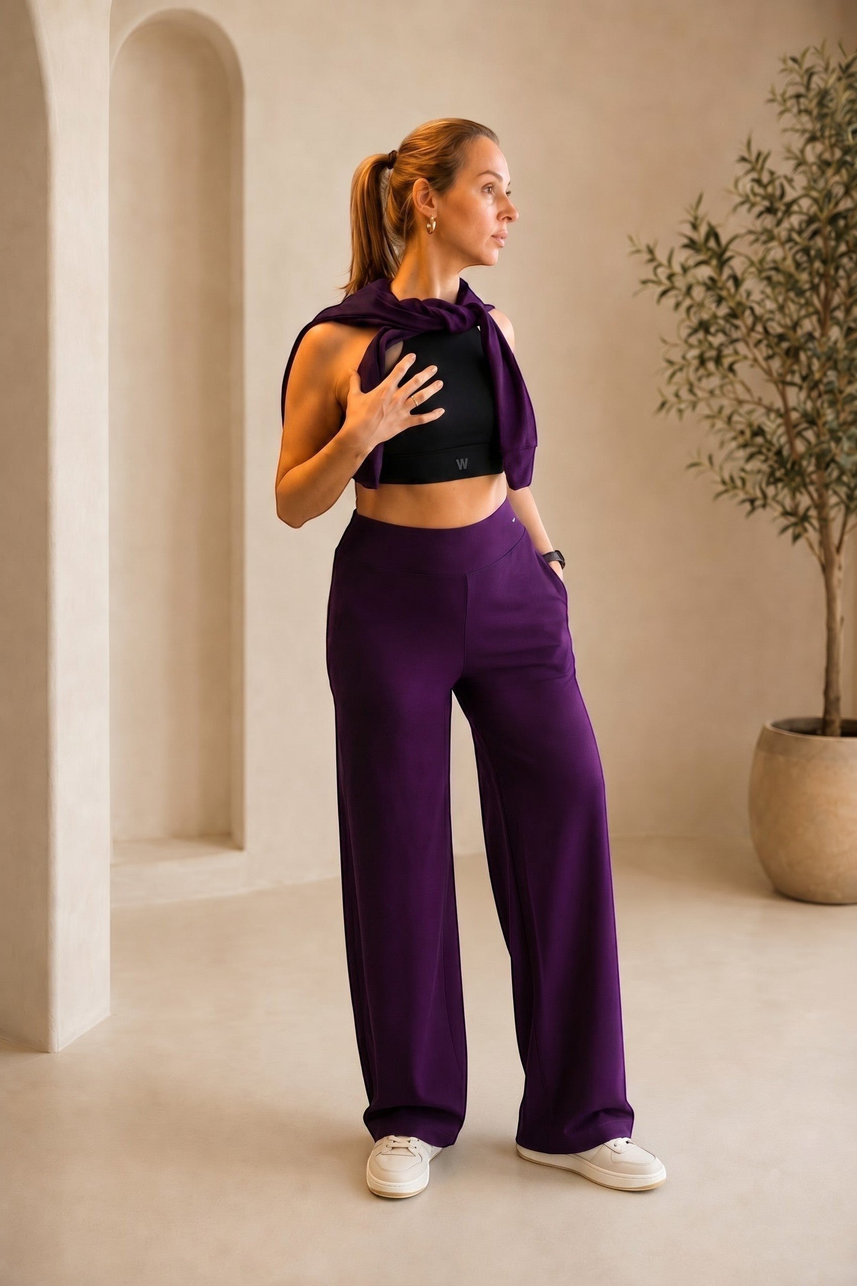 Modelo veste calça pantalona canelada W One Brand Store na cor vinho com blusa preta em ambiente minimalista