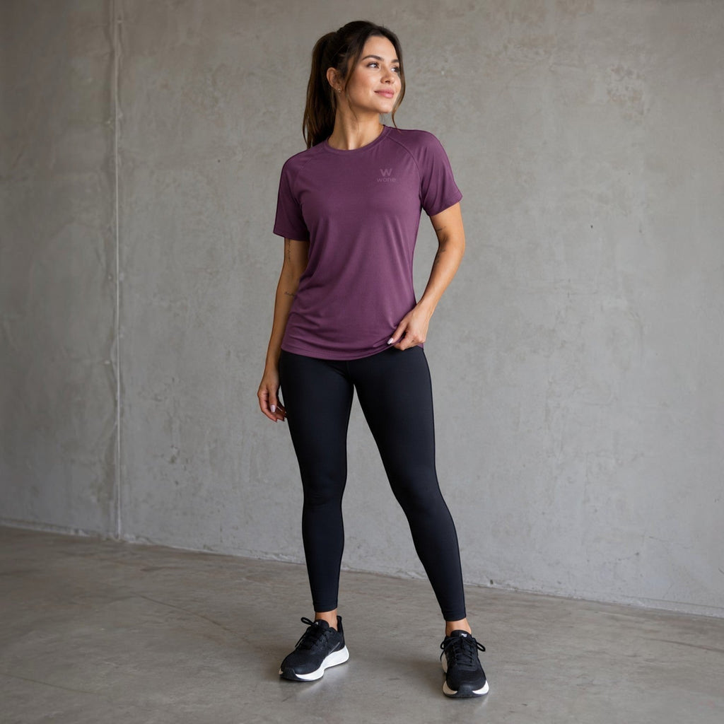 Mulher vestindo camiseta W One Brand Store Dynamic Wine com mangas raglan, tecido respirável e proteção solar FPU 50+
