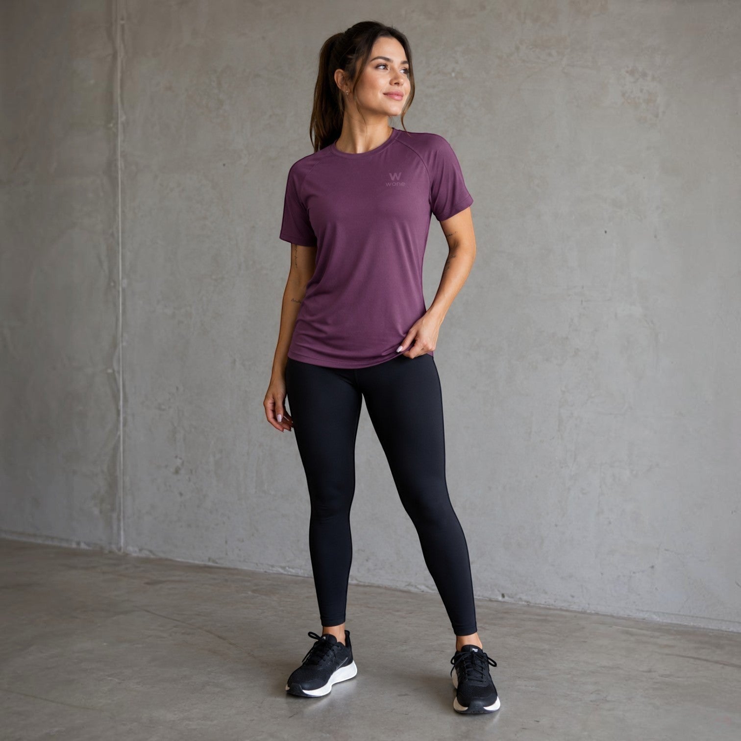 Mulher vestindo camiseta W One Brand Store Dynamic Wine com mangas raglan, tecido respirável e proteção solar FPU 50+