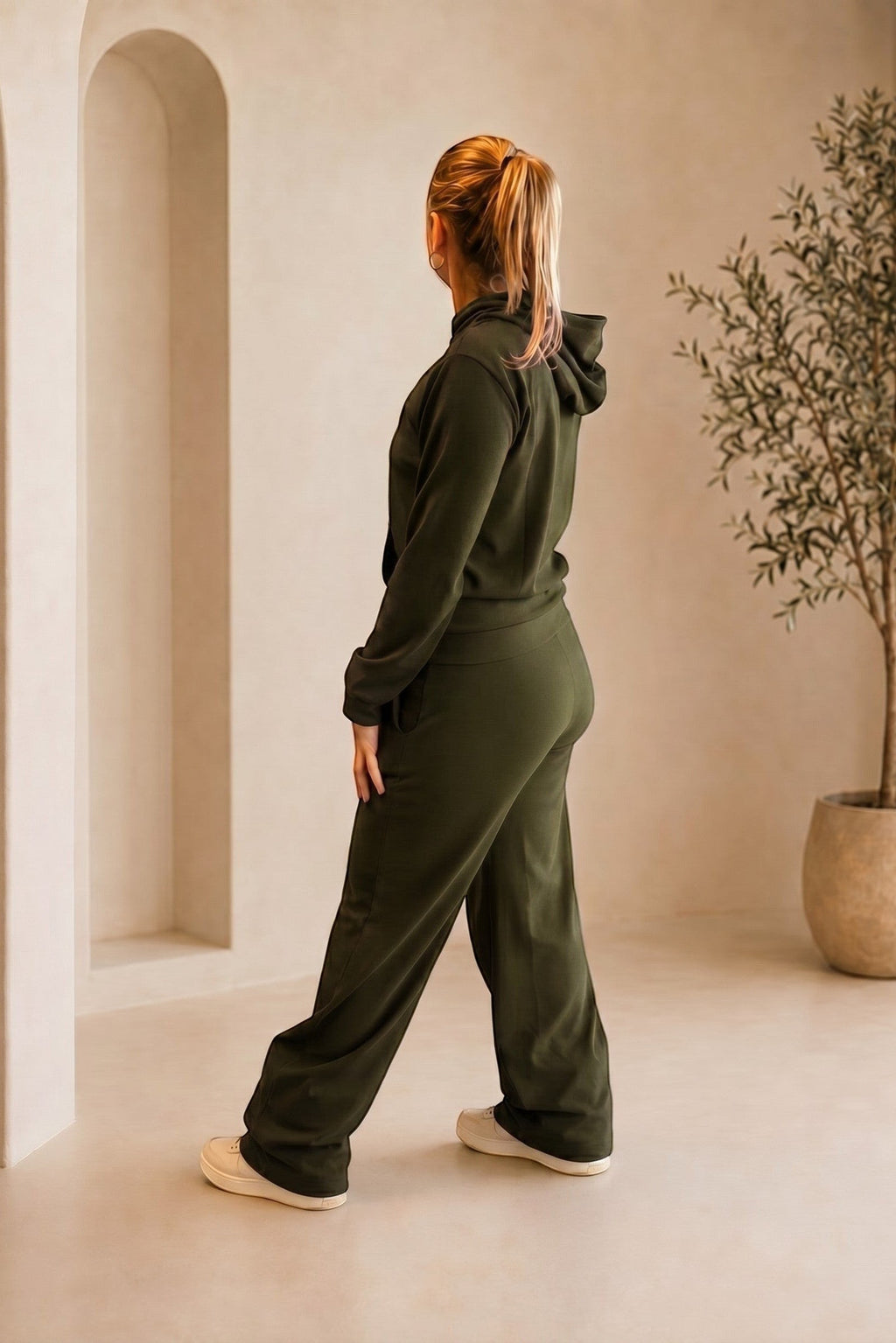 Mulher vestindo conjunto W One Brand Store verde militar canelado com blusa de capuz e calça pantalona em ambiente