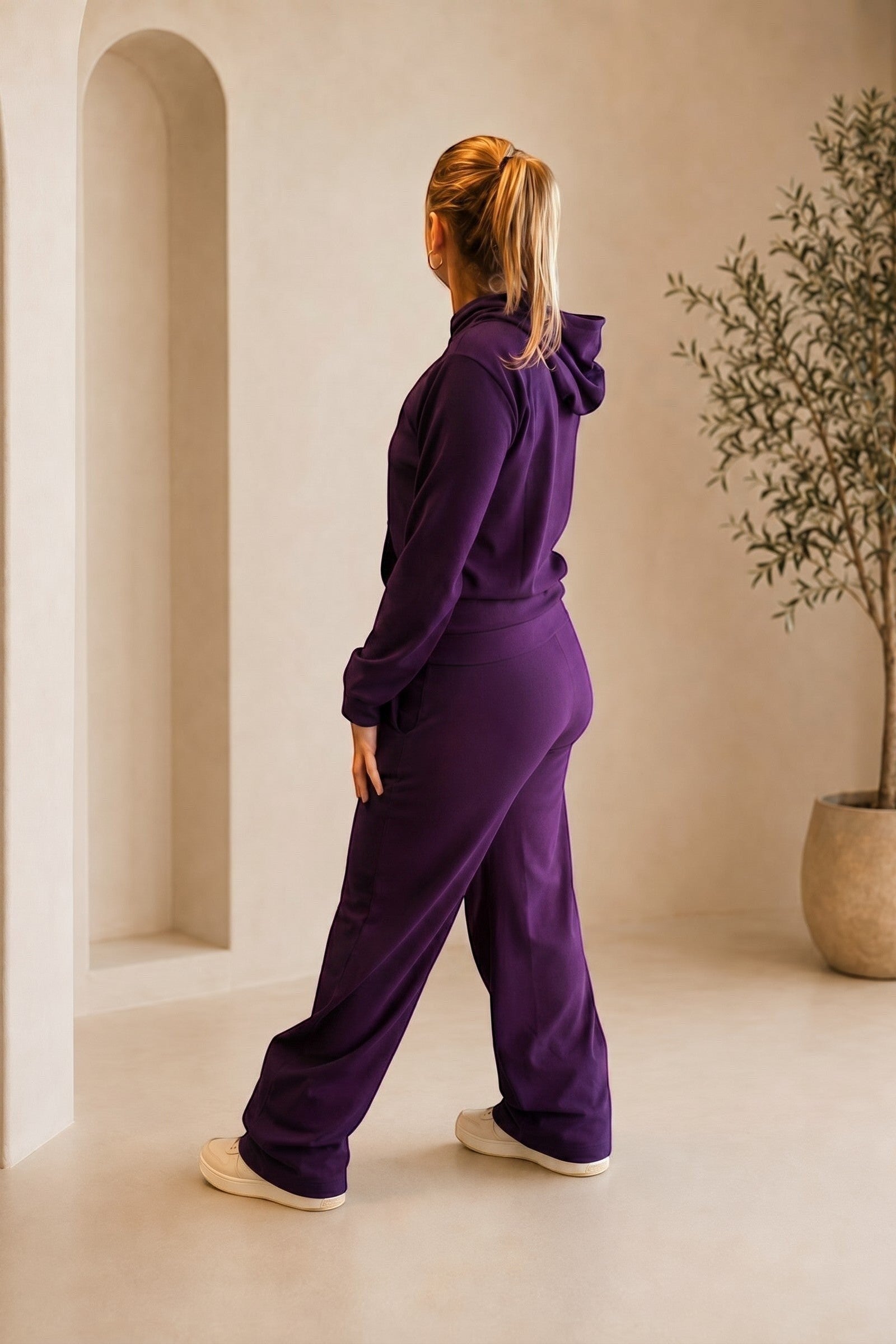 Mulher vestindo conjunto W One Brand Store cor vinho com blusa de capuz canelada e calça pantalona em ambiente neutro