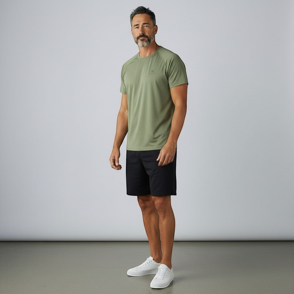 W One Brand Store men's green polyamide t-shirt with raglan sleeves and a subtle logo. Model is wearing black shorts and white sneakers.