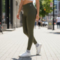 Legging W One Brand Store verde militar com bolso em V, modelagem performance ajustada ao corpo em ambiente urbano.