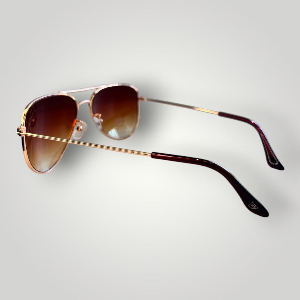 Óculos de sol aviador W One Brand Store com armação de metal dourado e lentes marrons degradê em vista lateral