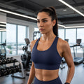 Modelo vestindo top esportivo W One Brand Store azul marinho com modelagem nadador e alta sustentação em academia