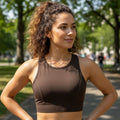 Mulher usando top esportivo marrom W One Brand Store de alta sustentação em tecido respirável em parque ao ar livre