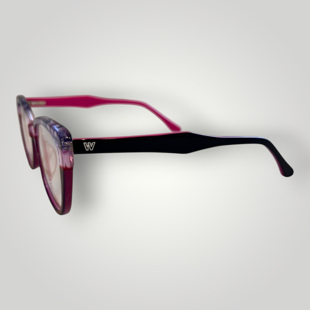 Óculos de grau W One feminino, armação gatinho em acetato rosa e roxo com hastes externas roxas e internas rosa. Logo W em destaque.